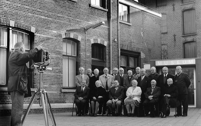 Groepsfoto voor de ingang van het Textielmuseum. Ongedateerd. Fotograaf Rien Siers, Tilburg. Uit de collectie van het Regionaal Archief Tilburg.